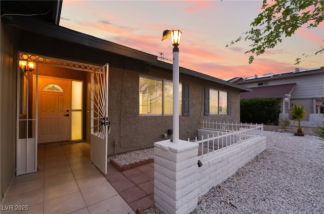 view of side of property with stucco siding and fence
