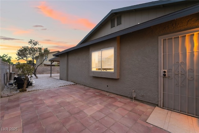 exterior space with fence, a patio, and stucco siding
