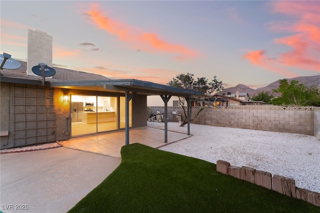 back of property with a fenced backyard, stucco siding, a patio, a chimney, and a mountain view