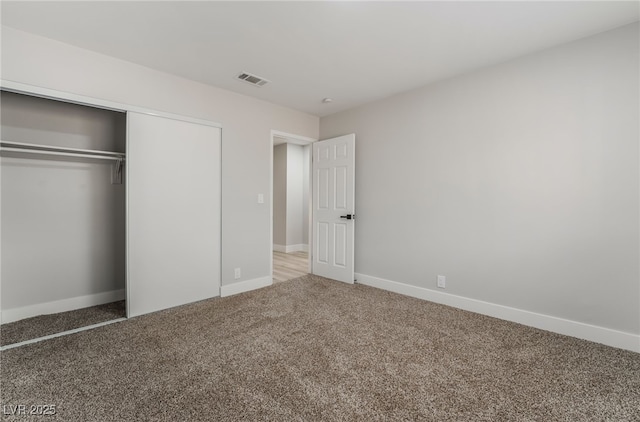 unfurnished bedroom with a closet, visible vents, baseboards, and carpet