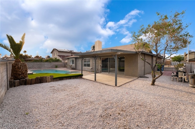 rear view of property featuring a patio area, a fenced backyard, a fenced in pool, and stucco siding