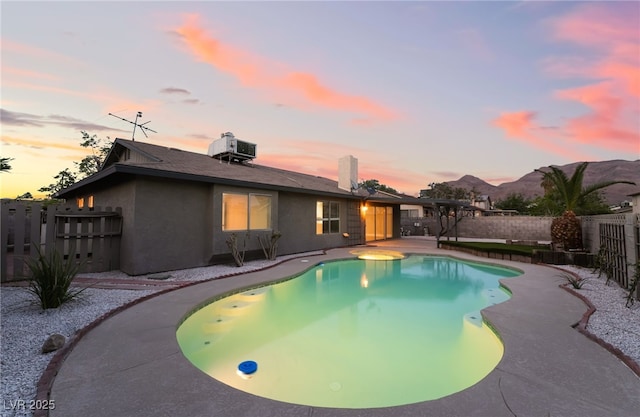 pool at dusk with cooling unit, a fenced backyard, a fenced in pool, and a patio area