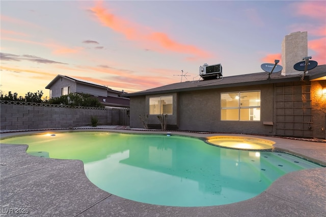 view of swimming pool with a fenced backyard, a pool with connected hot tub, central AC unit, and a patio area