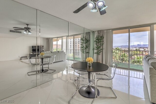 tiled dining area featuring visible vents, ceiling fan, and floor to ceiling windows