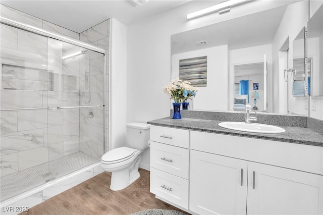 full bathroom with visible vents, a shower stall, wood finished floors, vanity, and toilet