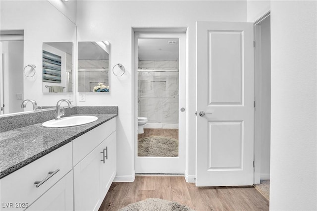 full bath featuring vanity, toilet, baseboards, a shower stall, and wood finished floors