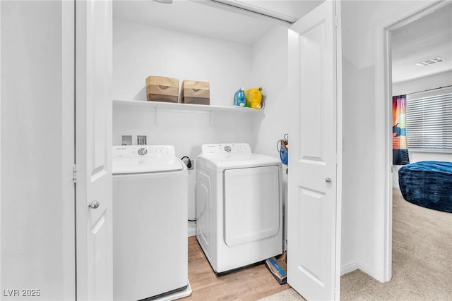 clothes washing area with visible vents, laundry area, light wood finished floors, and washing machine and dryer