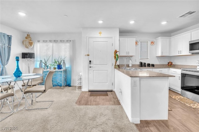 kitchen with visible vents, light wood-style floors, white cabinetry, a sink, and stainless steel appliances