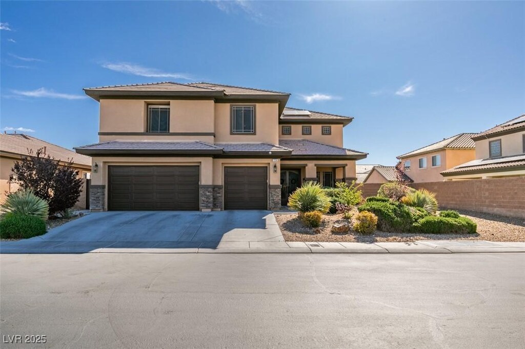 prairie-style home with stone siding, a garage, fence, concrete driveway, and stucco siding