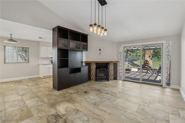 unfurnished living room featuring baseboards, a fireplace, and lofted ceiling