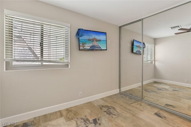 unfurnished bedroom with wood finished floors, baseboards, a closet, and visible vents