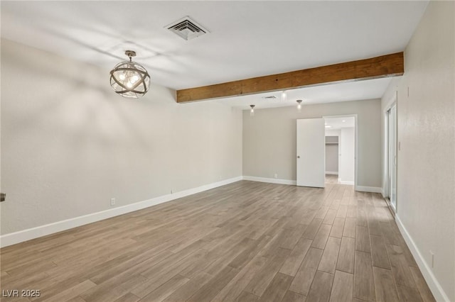 empty room featuring wood finished floors, beamed ceiling, baseboards, and visible vents