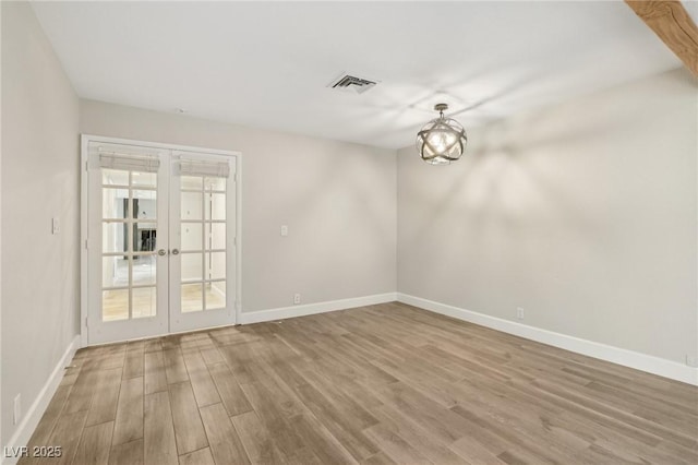 spare room with french doors, baseboards, visible vents, and wood finished floors