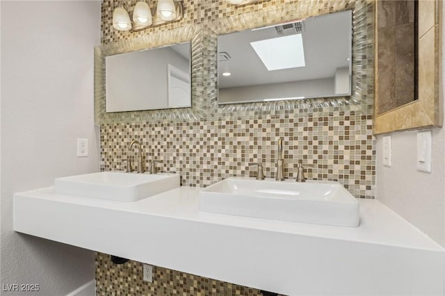 bathroom featuring visible vents, a sink, backsplash, and a skylight