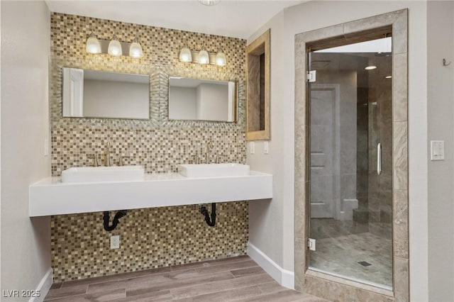 bathroom featuring a stall shower, a sink, backsplash, and baseboards