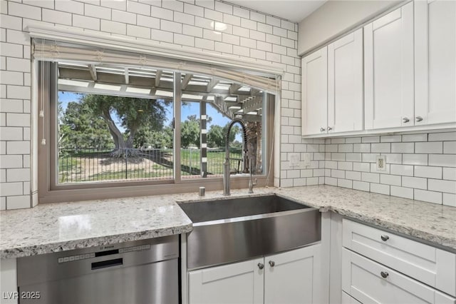 kitchen featuring a sink, stainless steel dishwasher, decorative backsplash, and a healthy amount of sunlight