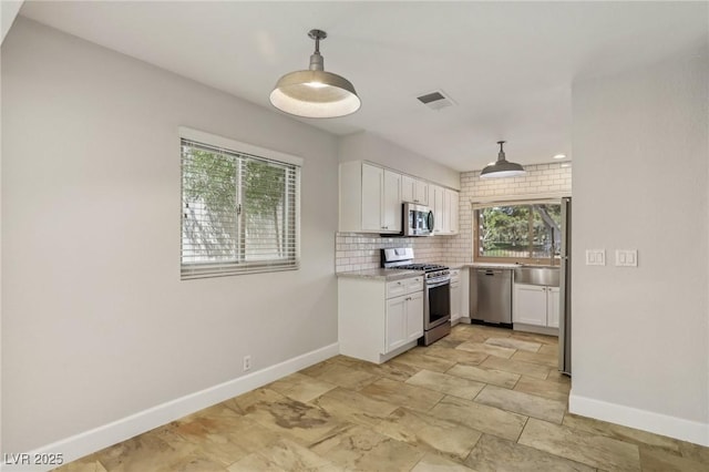 kitchen with white cabinetry, tasteful backsplash, baseboards, and appliances with stainless steel finishes