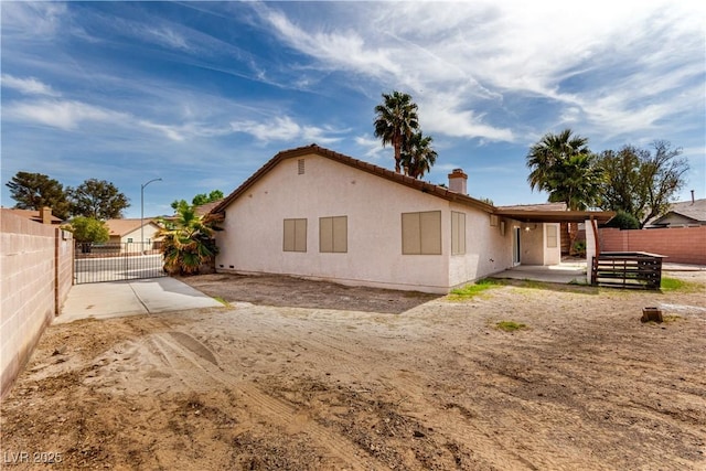 rear view of property featuring a patio, stucco siding, fence, and a chimney