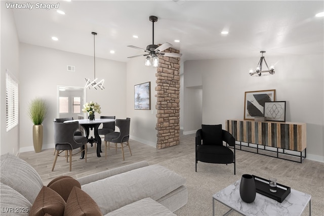 living area featuring visible vents, baseboards, decorative columns, recessed lighting, and ceiling fan with notable chandelier