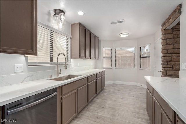 kitchen with light wood-style flooring, visible vents, dishwasher, a sink, and baseboards