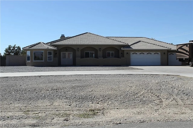 view of front facade featuring stucco siding, a tile roof, an attached garage, a chimney, and driveway