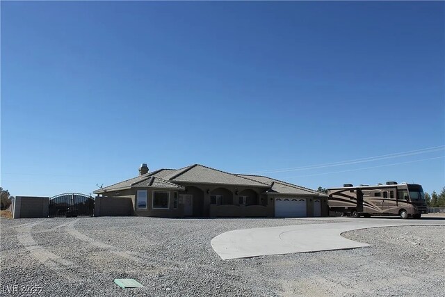view of front of home featuring stucco siding, a gate, a chimney, and curved driveway