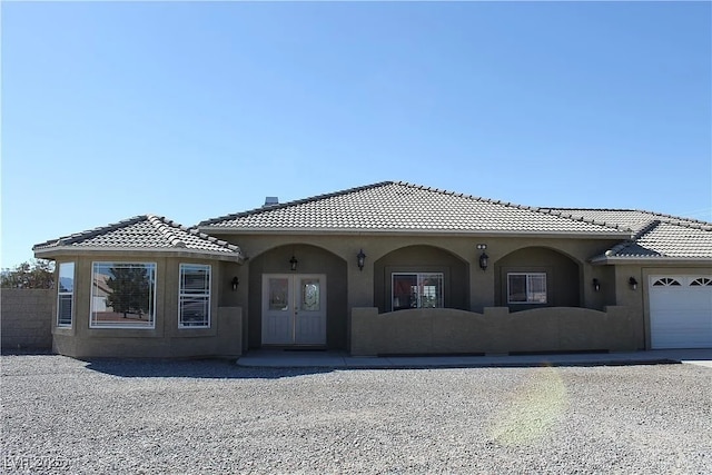 view of front facade featuring a tile roof, fence, a garage, and stucco siding