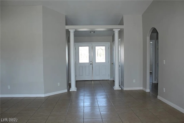 entrance foyer featuring arched walkways, tile patterned floors, and baseboards