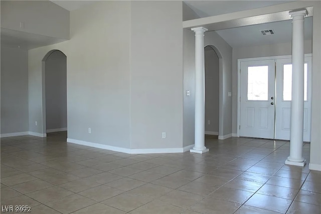spare room featuring arched walkways, light tile patterned floors, baseboards, and visible vents