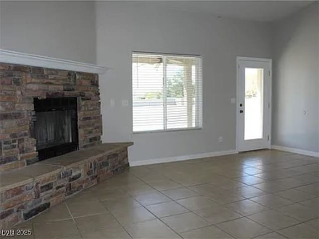 unfurnished living room featuring a fireplace, baseboards, and tile patterned flooring