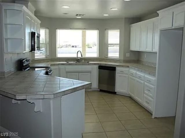 kitchen featuring stainless steel appliances, a peninsula, white cabinetry, and light tile patterned floors