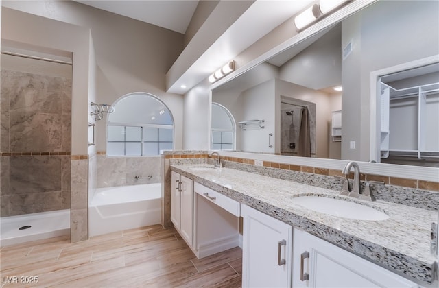full bath featuring a sink, double vanity, a stall shower, and a garden tub