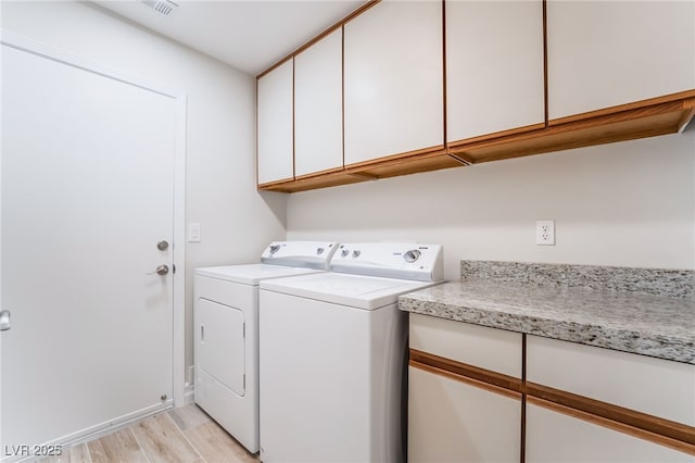laundry area featuring independent washer and dryer, light wood-style floors, visible vents, and cabinet space