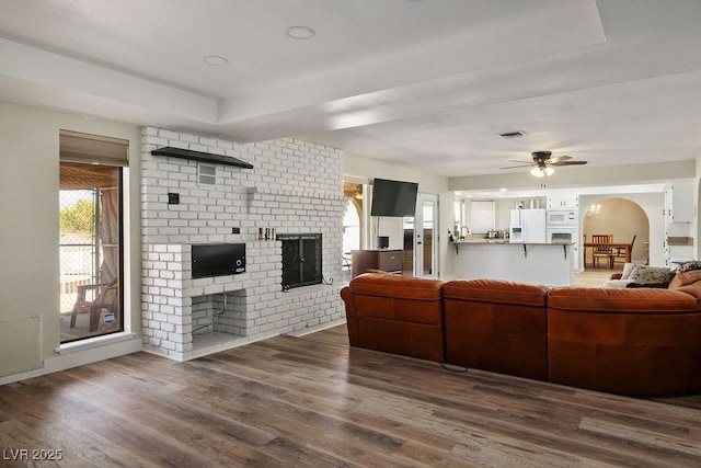 1410 E Serene Ave, Las Vegas, NV 89123 - living room featuring a fireplace, a raised ceiling, a ceiling fan, visible vents, and wood finished floors