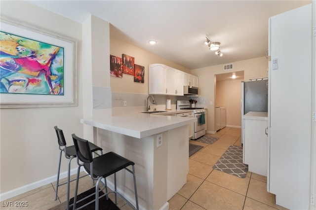 7945 Delbonita Ave, Las Vegas, NV 89147 - kitchen with white cabinets, a sink, appliances with stainless steel finishes, a breakfast bar, and independent washer and dryer