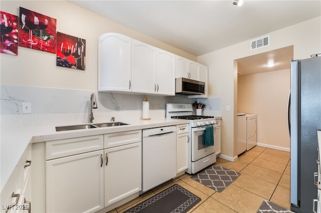7945 Delbonita Ave, Las Vegas, NV 89147 - kitchen with visible vents, a sink, white cabinetry, stainless steel appliances, and washer and clothes dryer