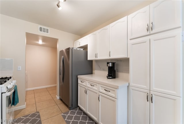 7945 Delbonita Ave, Las Vegas, NV 89147 - kitchen with light tile patterned floors, light countertops, freestanding refrigerator, gas range gas stove, and white cabinets