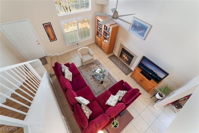 7945 Delbonita Ave, Las Vegas, NV 89147 - tiled living room featuring baseboards, a ceiling fan, a towering ceiling, and a glass covered fireplace