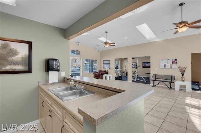 7945 Delbonita Ave, Las Vegas, NV 89147 - kitchen featuring vaulted ceiling with skylight, ceiling fan, light tile patterned floors, a sink, and open floor plan