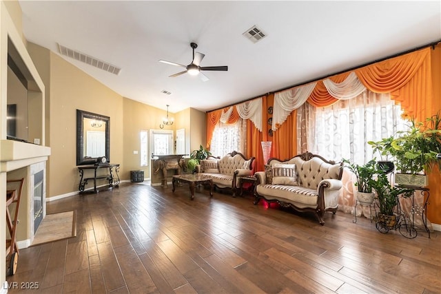 living room featuring dark wood finished floors, vaulted ceiling, visible vents, and a ceiling fan