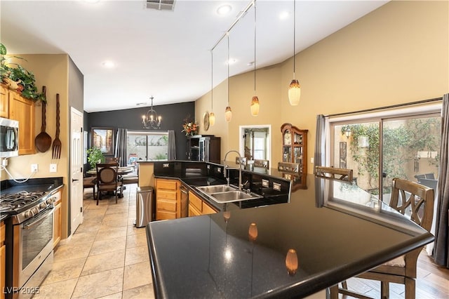 kitchen featuring stainless steel appliances, an inviting chandelier, dark countertops, vaulted ceiling, and a sink
