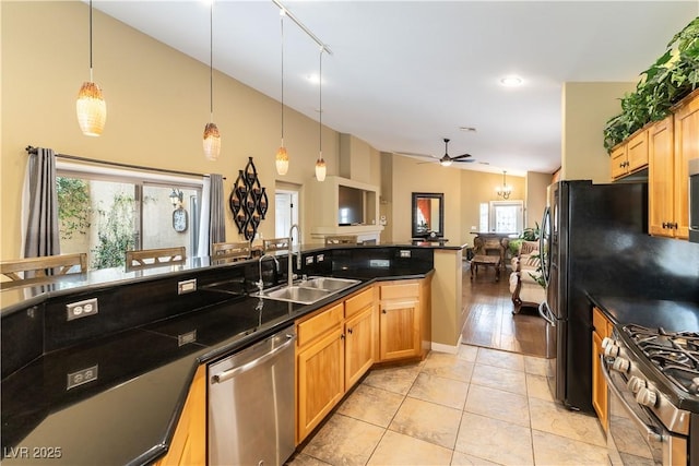 kitchen featuring a sink, dark countertops, open floor plan, a ceiling fan, and appliances with stainless steel finishes