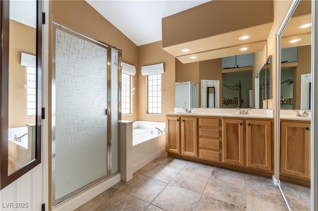bathroom with double vanity, a shower stall, a garden tub, and a sink