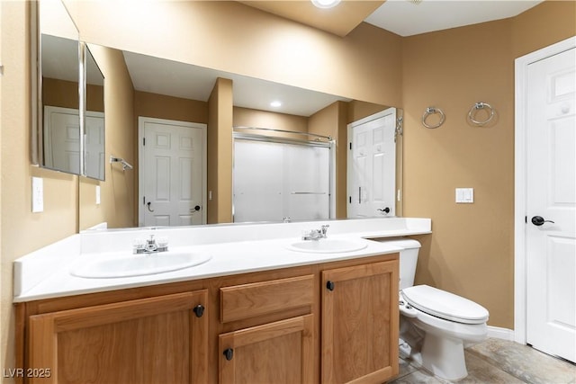 full bathroom featuring double vanity, toilet, a shower with door, and a sink