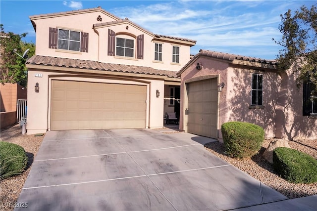 mediterranean / spanish home with concrete driveway, an attached garage, a tile roof, and stucco siding