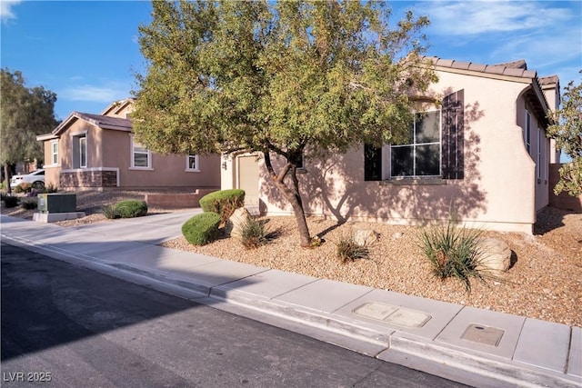 view of front facade with an attached garage, driveway, and stucco siding
