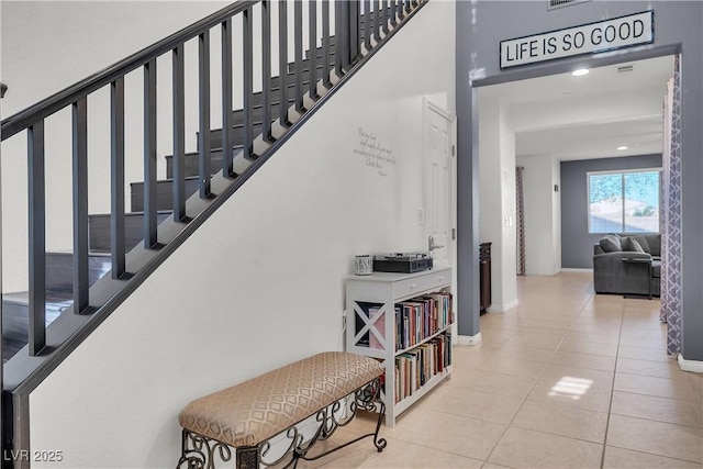 stairs featuring baseboards, tile patterned flooring, and a high ceiling