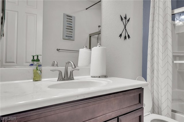 full bath featuring toilet, vanity, a shower with shower curtain, and a textured wall