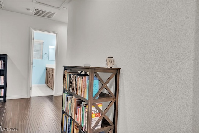 hall with visible vents, baseboards, a textured wall, and dark wood-style floors