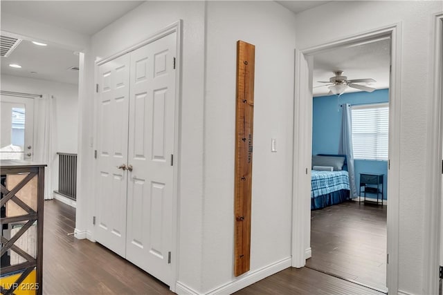 corridor featuring recessed lighting, dark wood-style flooring, baseboards, and visible vents